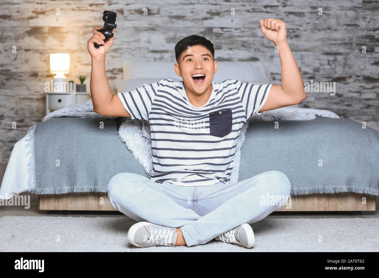 Uomo asiatico che gioca a casa in serata Foto Stock