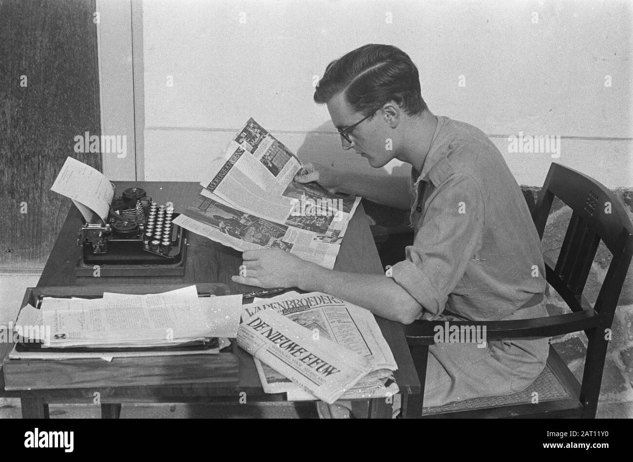 Un editore legge una copia della rivista Brothers of Arms, seduta su una scrivania con macchina da scrivere. Legge un articolo sul servizio Welfare Data: Ottobre 1947 Località: Indonesia, Indie Orientali Olandesi Foto Stock