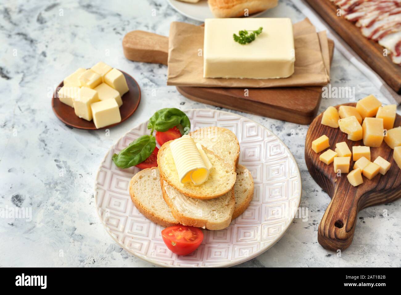 Fette di pane con burro fresco e formaggio su fondo bianco Foto Stock