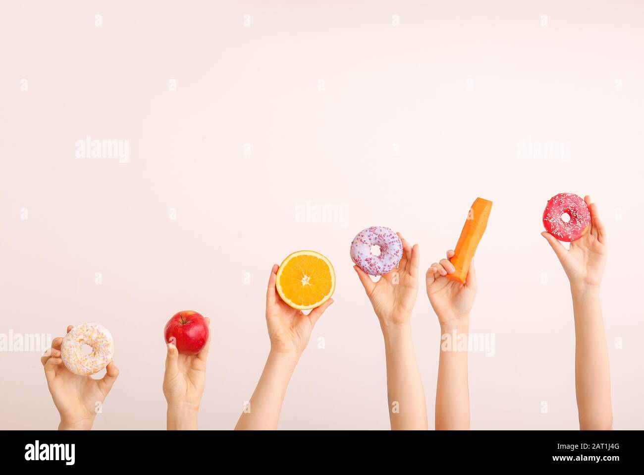 Mani femminili con ciambelle dolci, carote e arancio su sfondo colorato Foto Stock
