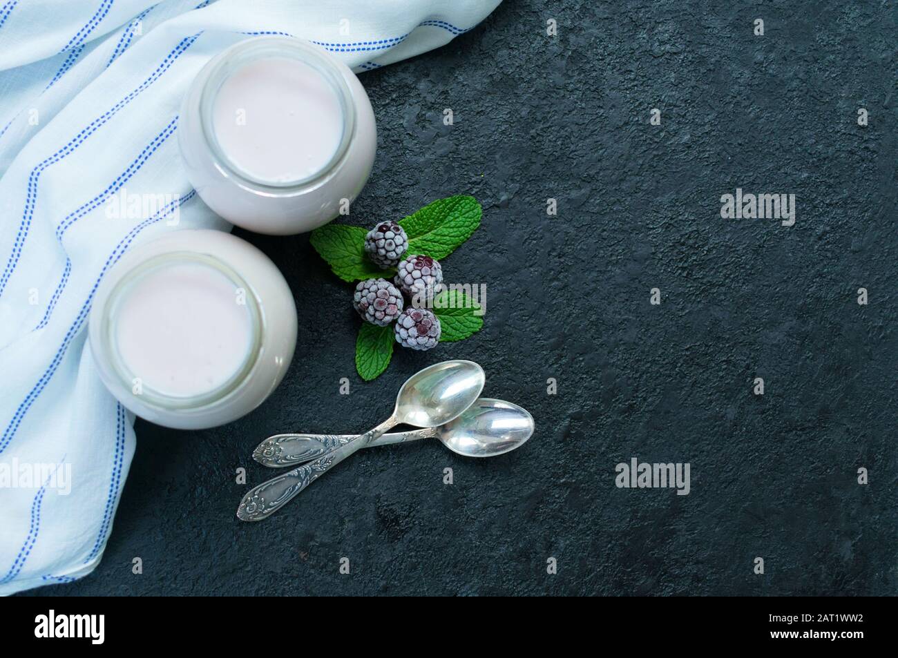 Due vasetti di yogurt blackberry su sfondo nero. Spazio di copia. Vista dall'alto. Foto Stock