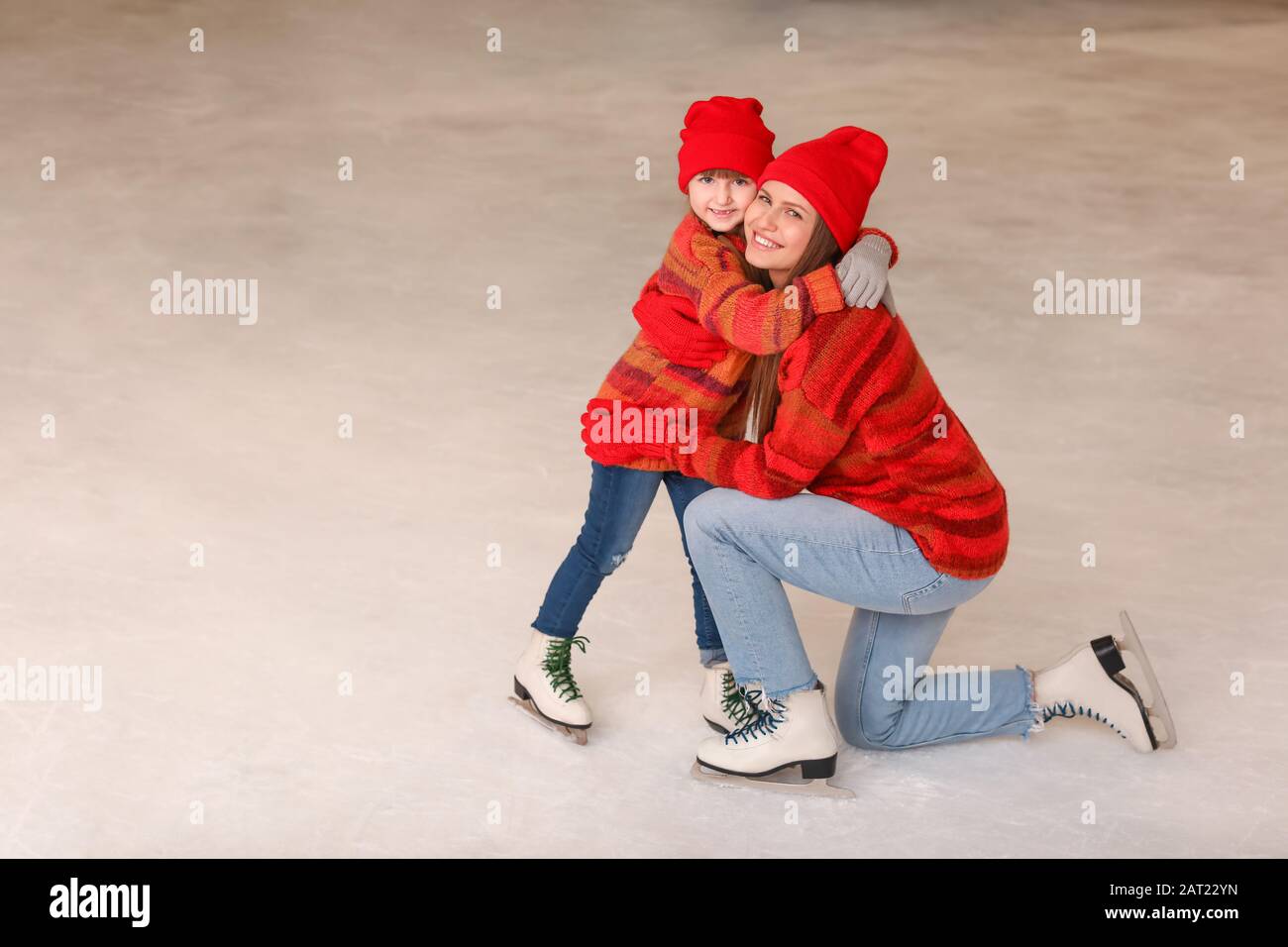 Giovane madre con piccola figlia sulla pista di pattinaggio Foto Stock