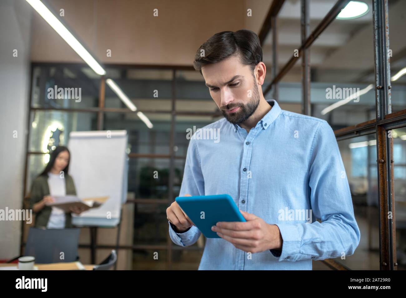 Bell'uomo con un tablet in mano che guarda coinvolto Foto Stock