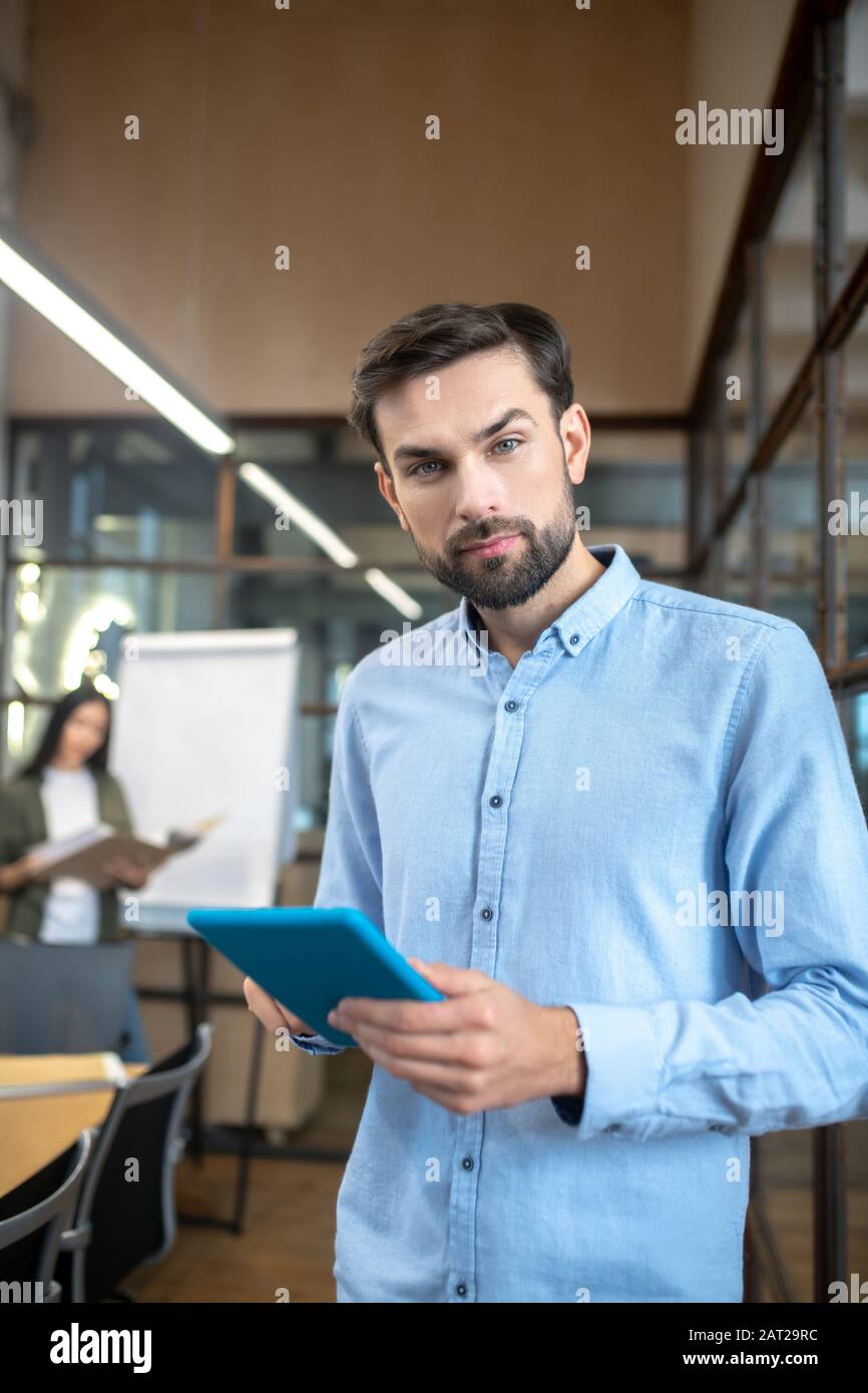 Bell'uomo con un tablet nelle mani che guarda serio Foto Stock