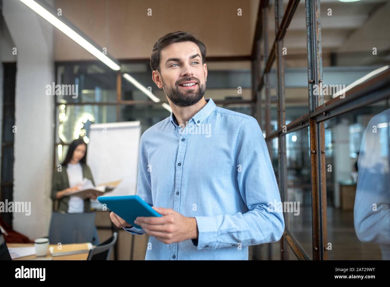 Bell'uomo con un tablet in mano che guarda pensieroso Foto Stock