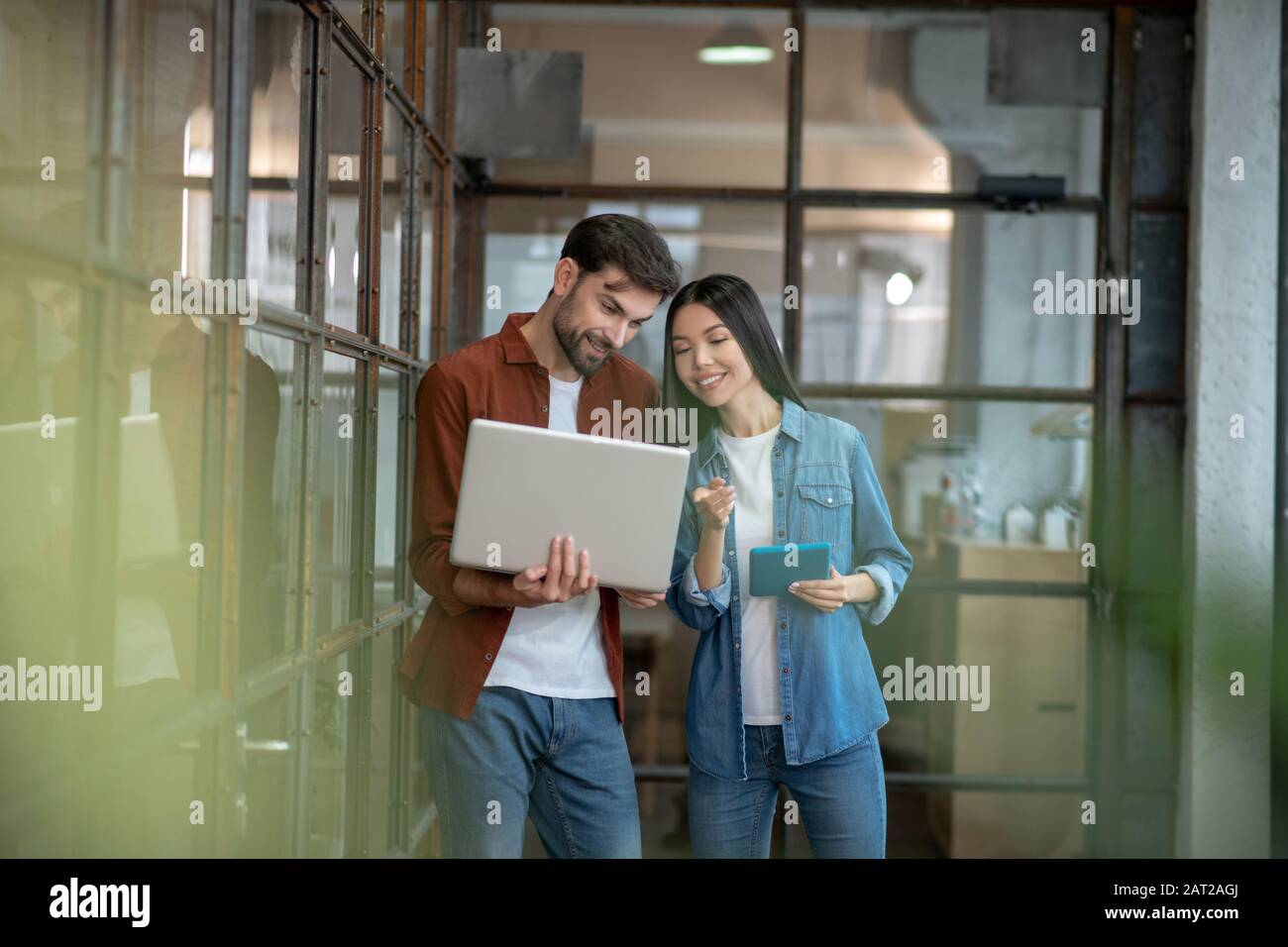 Bell'uomo barbuto in una camicia marrone che discute di questioni di lavoro con il collega Foto Stock