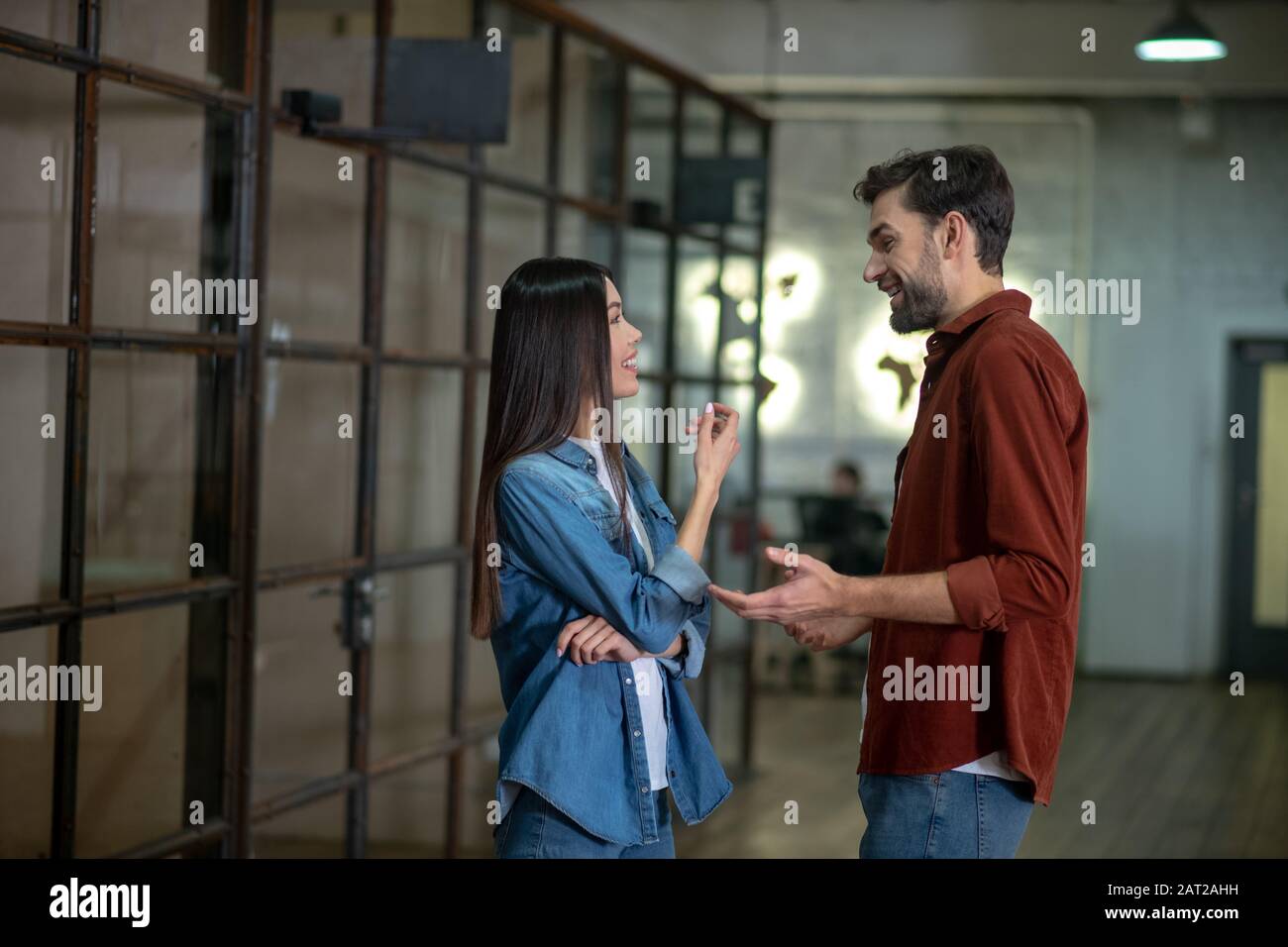 Bell'uomo bearded in una camicia marrone che discute qualcosa con il suo collega femminile Foto Stock