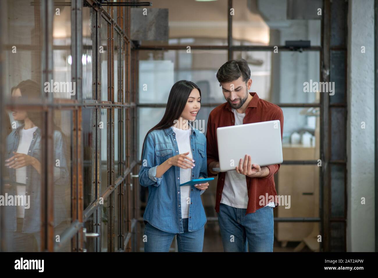 Bell'uomo barbuto in una camicia marrone che discute i problemi di lavoro con il collega Foto Stock