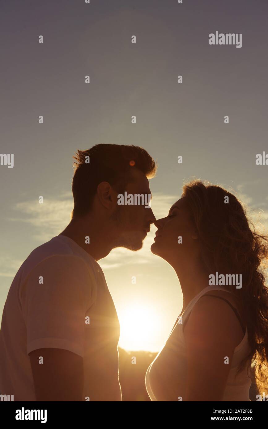 Primo piano ritratto di due giovani amanti baciare sul tramonto Foto Stock