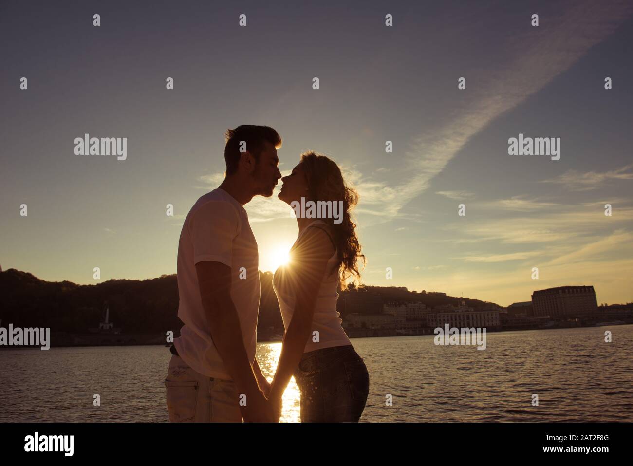 Silhouette di coppia in amore baciare e guardare al tramonto Foto Stock