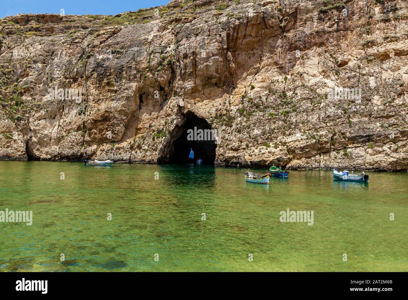 Una bella vista con una barca bianca turistica di fronte alla grotta marina in una giornata di sole. Ci sono molte barche vicino all'ingresso di una grotta. Foto Stock