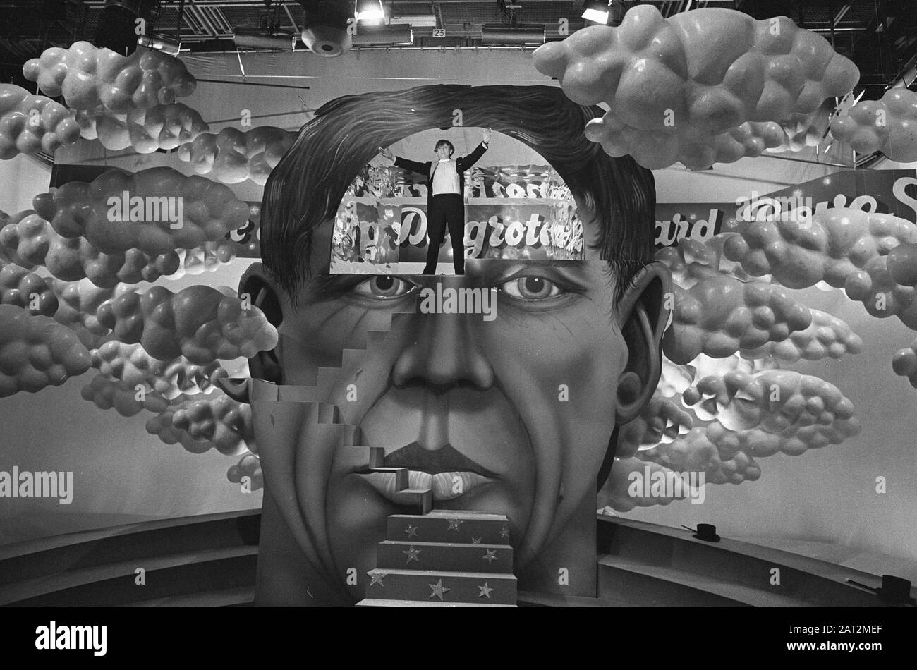 NOS prende il Gerard Reveshhow su Gerard Reve si alza con le braccia sollevate di fronte ad un'immagine del suo volto Data: 12 marzo 1974 Parole Chiave: Autori, programmi televisivi Nome personale: Reve, Gerard del Foto Stock