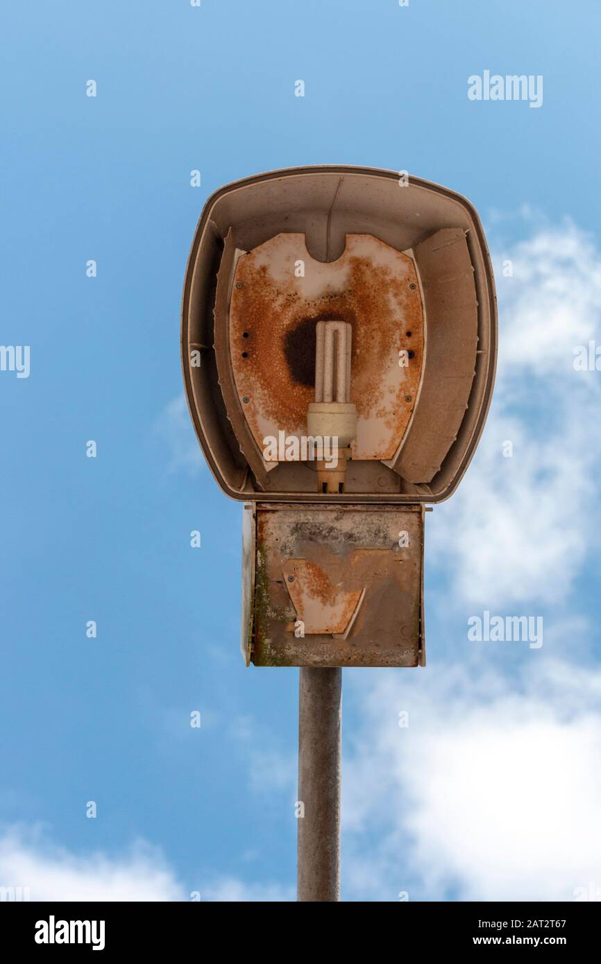 Una vista ravvicinata di una vecchia luce di strada esterna rotta con il grande cielo blu sopra di esso Foto Stock