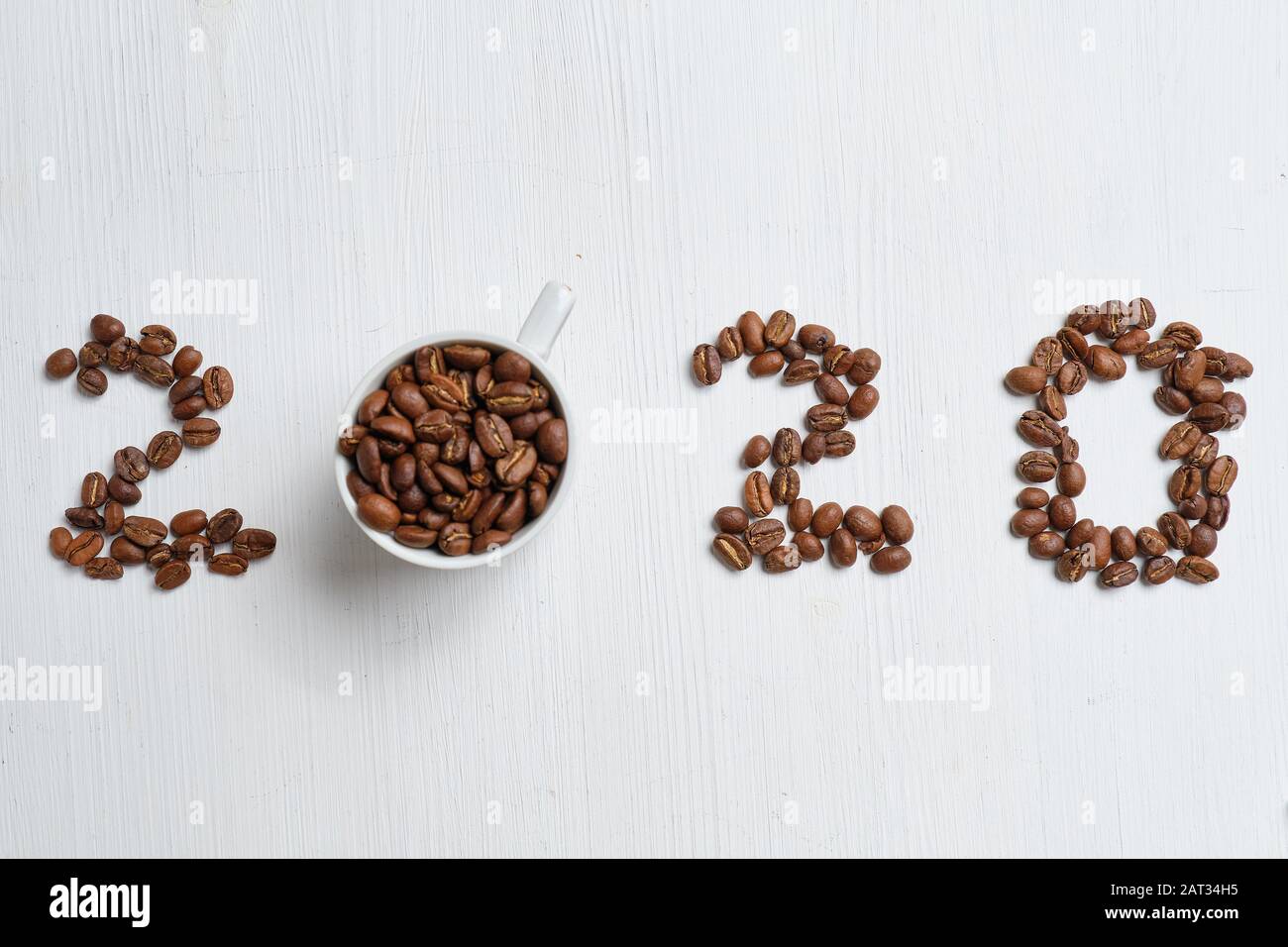 Figure astratte 2020 da chicchi di caffè e tazze bianche su sfondo ligneo. Primo piano. Foto Stock
