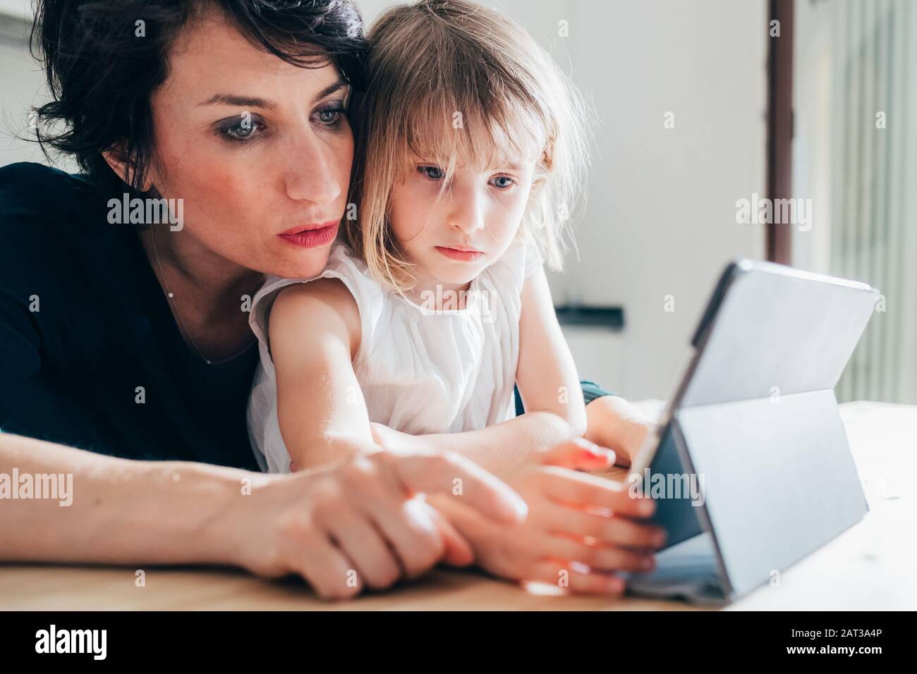 Madre e figlia indoor utilizzando tablet - learning, intrattenimento, concetto di insegnamento Foto Stock