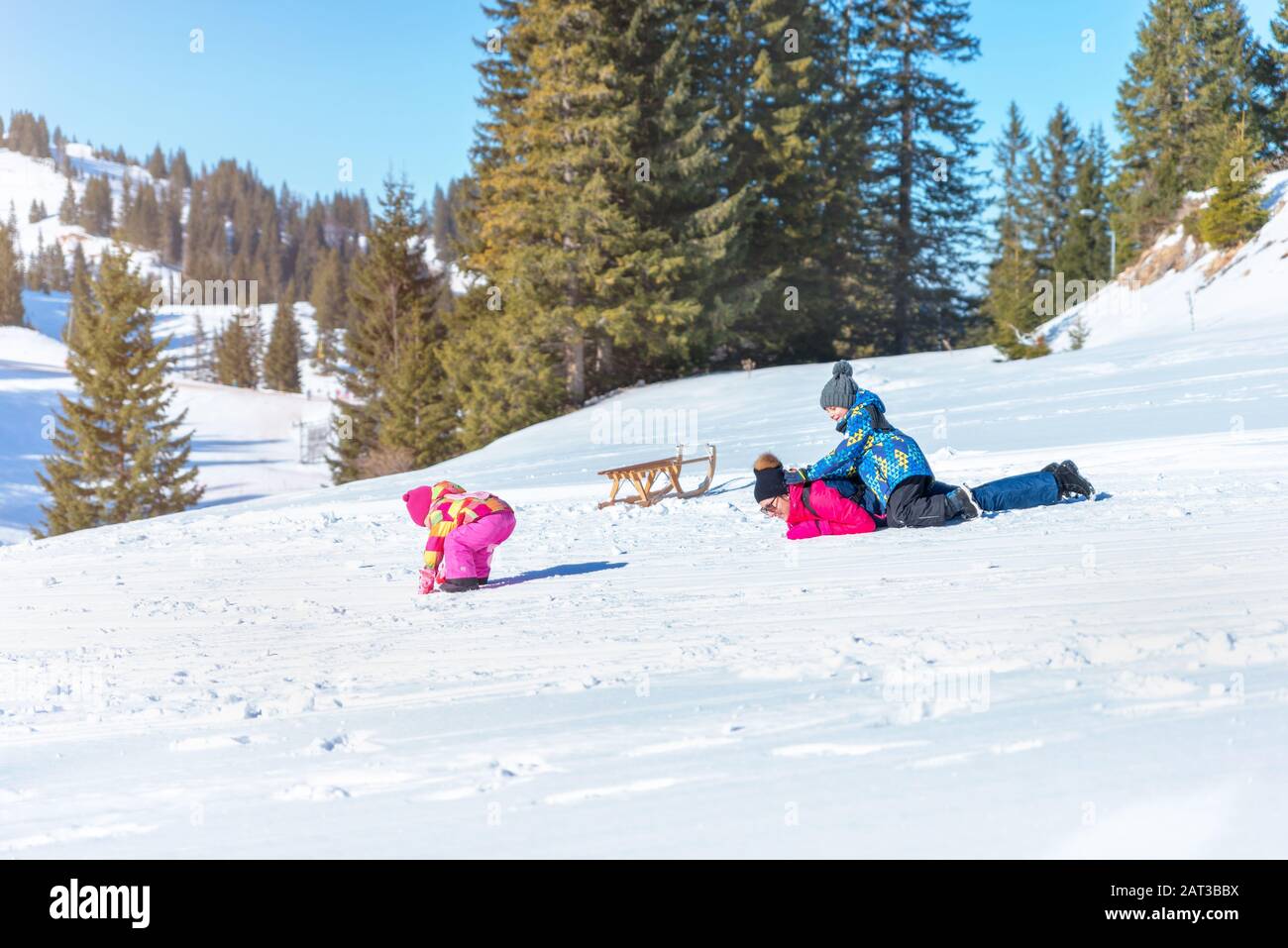 Madre che gioca con i bambini nella neve sulla montagna. Concetto di spendere tempo sulla neve e di aumentare la salute dei bambini Foto Stock