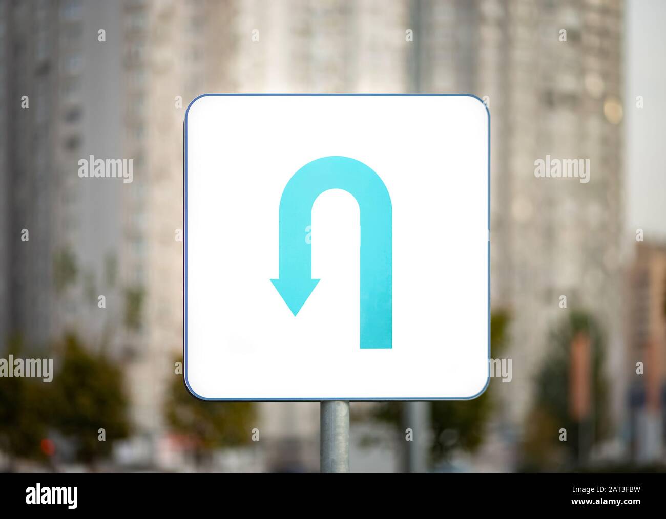 U-turn strada segno su sfondo urbano blurry Foto Stock