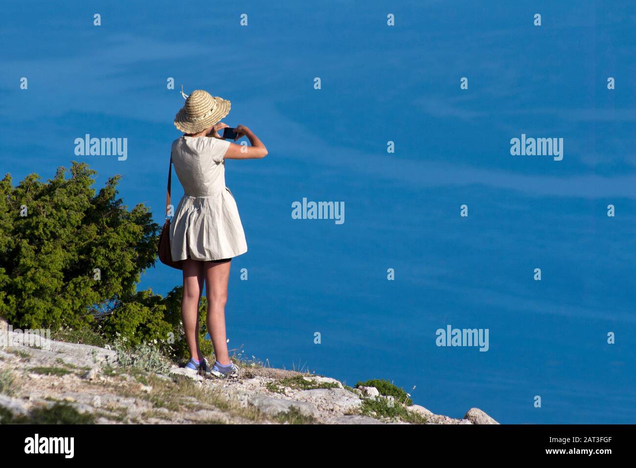 Giovane donna scatta foto del mare Adriatico blu turchese Foto Stock