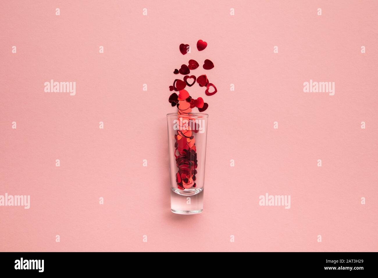 Foto di San Valentino. Bicchierino con confetti di cuore su sfondo rosa pastello Foto Stock