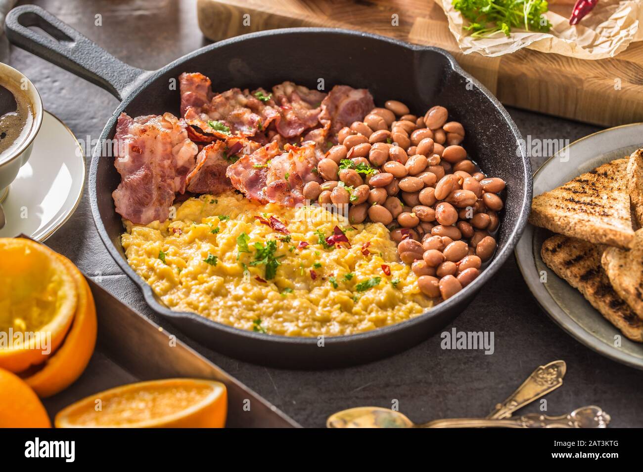 Tavolo completo con colazione all'inglese. Uova strapazzate pancetta fagioli grigliati pane tostato succo d'arancia e caffè Foto Stock