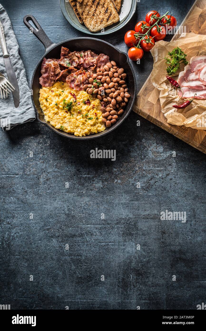 Colazione all'inglese uova strapazzate con pancetta e pane tostato alla griglia - vista dall'alto Foto Stock