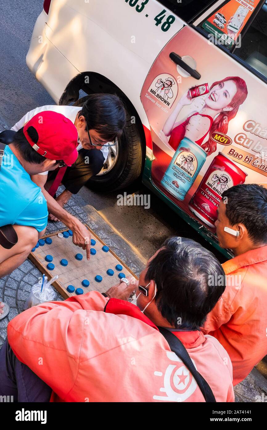 Uomini che giocano un gioco da tavolo sulla strada, ho Chi Minh City, Vietnam Foto Stock