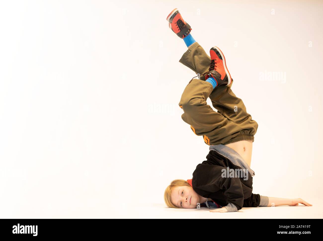 un ragazzino esegue una figura unica di breakdance mentre si alza sulla spalla, un bambino unico, stile hi hop Foto Stock
