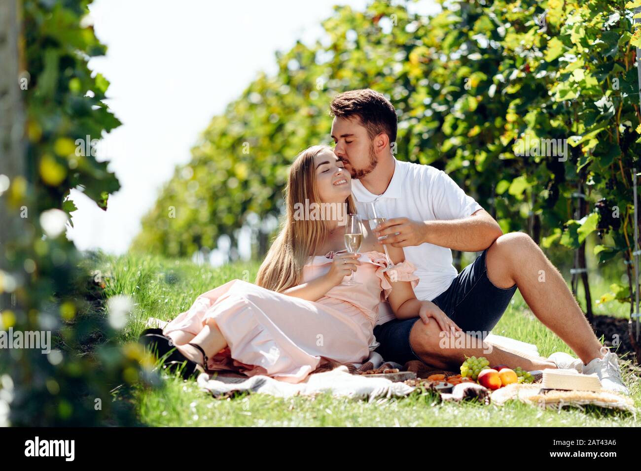 Coppia giovane amorevole che ha picnic ad un vigneto. Foto Stock