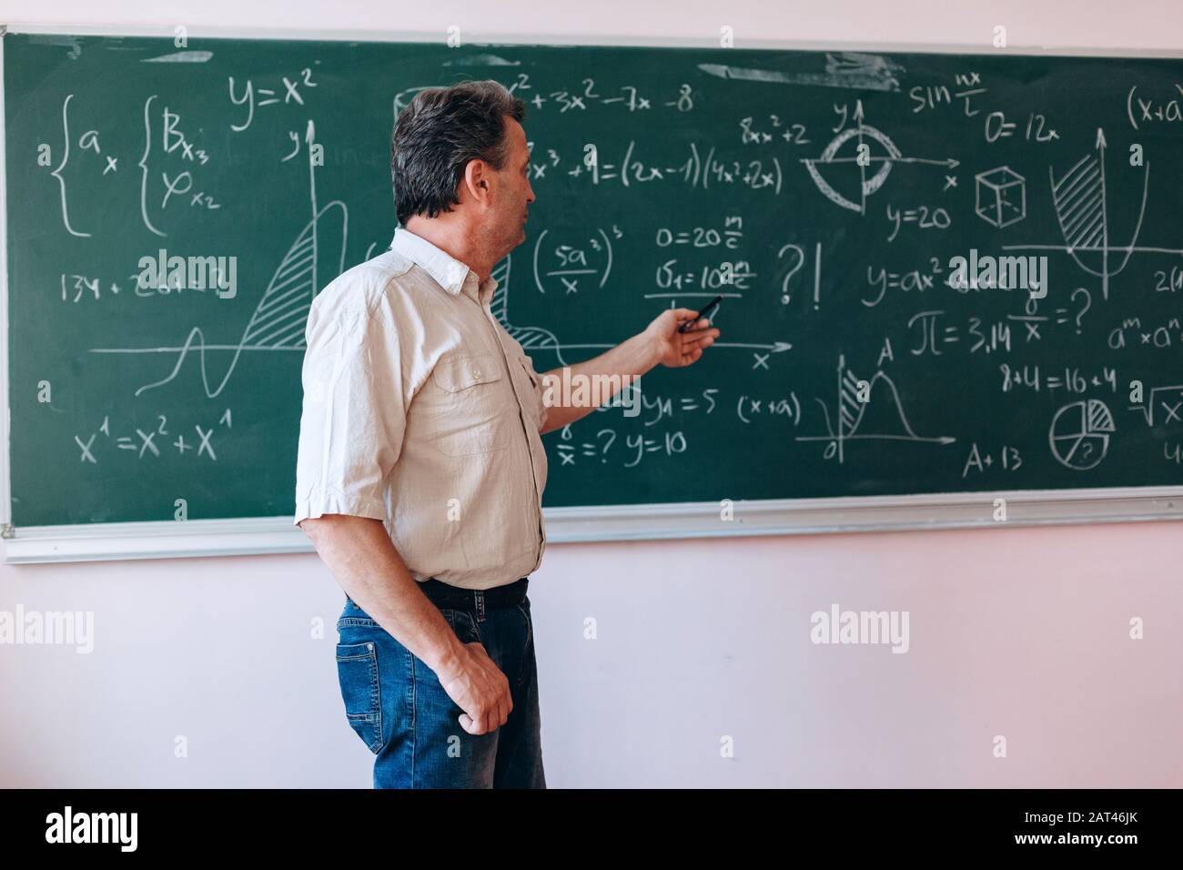 Insegnante che punta alla lavagna e spiega una lezione.- immagine Foto  stock - Alamy