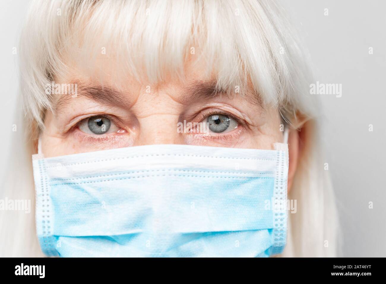 Donna adulta in maschera medica guarda la fotocamera. Protezione antivirus. Arrestare l'infezione da virus. Romanzo Coronavirus, 2019-nCoV Foto Stock