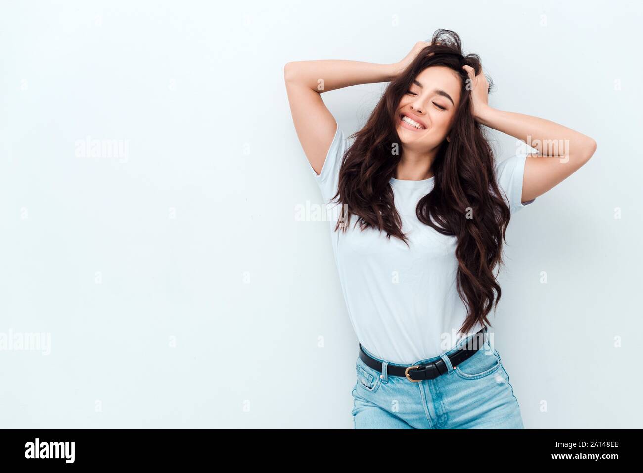 La giovane ragazza eccitata in una T-shirt bianca tiene la testa ed è veramente felice. Le persone le emozioni sincere sono uno stile di vita. Area pubblicitaria. Foto Stock