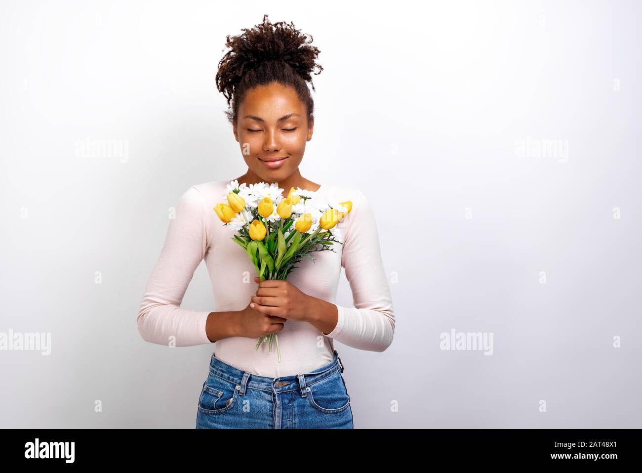 Ritratto di mezza lunghezza studio di meravigliosa ragazza con bouquet di tulipani fiori e margherite nelle sue mani Foto Stock