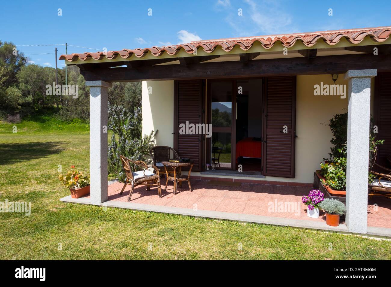Posto a sedere su una terrazza di un cottage sull'isola italiana della Sardegna in estate con cielo blu Foto Stock