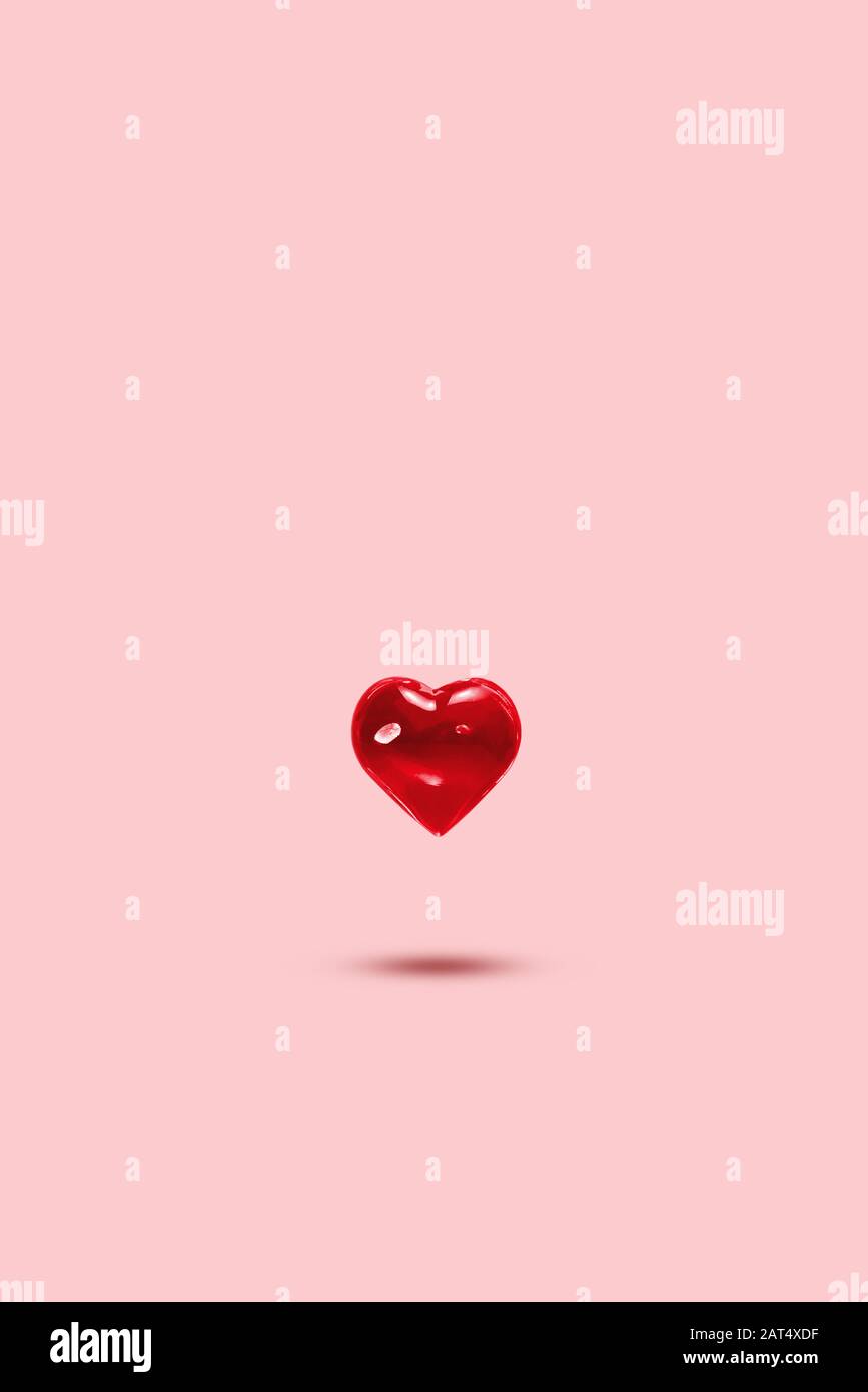 Cuore di vetro su sfondo pastello, levitazione. Simbolo dell'amore, minimalismo. Concetto di amore, San Valentino Foto Stock