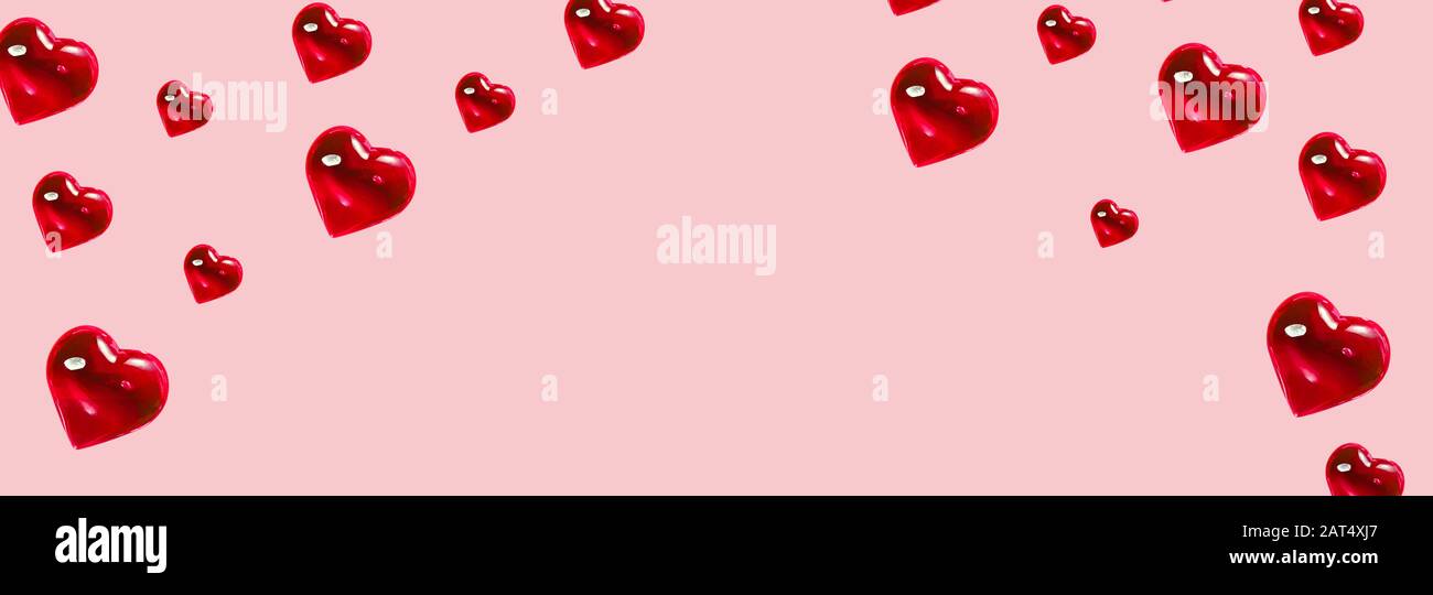San Valentino sfondo. Motivo di cuori rossi di vetro su sfondo rosa pastello. Minimalismo carta, simbolo di amore Banner Foto Stock