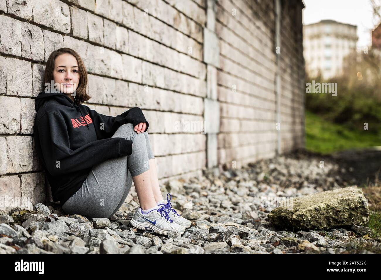 Ritratto di una ragazza sportiva del college di 17 anni che si posa contro un muro ruvido sotto un ponte a Molenbeek, Bruxelles, Belgio Foto Stock