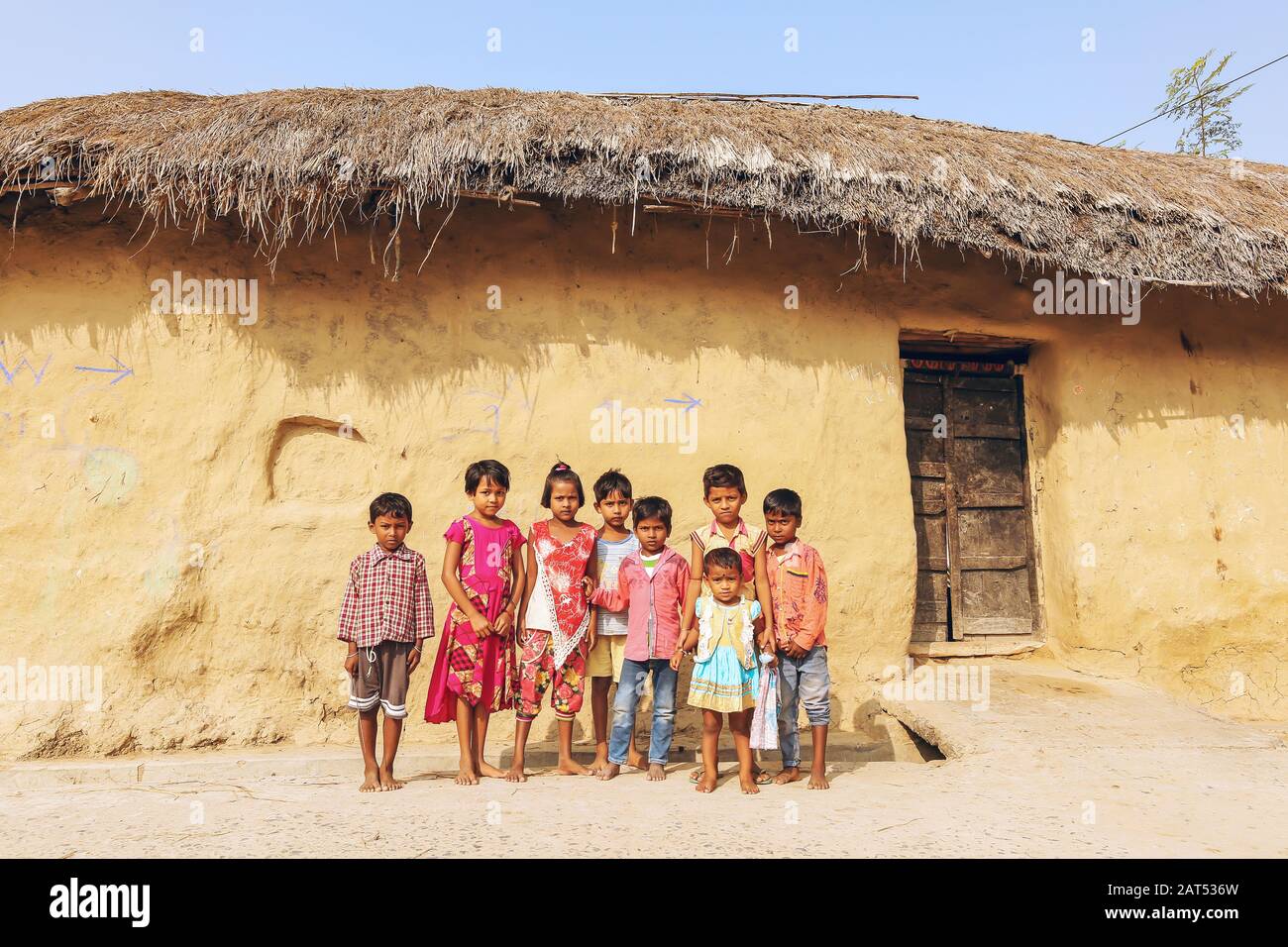 I bambini posano per una fotografia fuori di una capanna di fango ad un villaggio tribale a Bolpur, Bengala occidentale, India Foto Stock