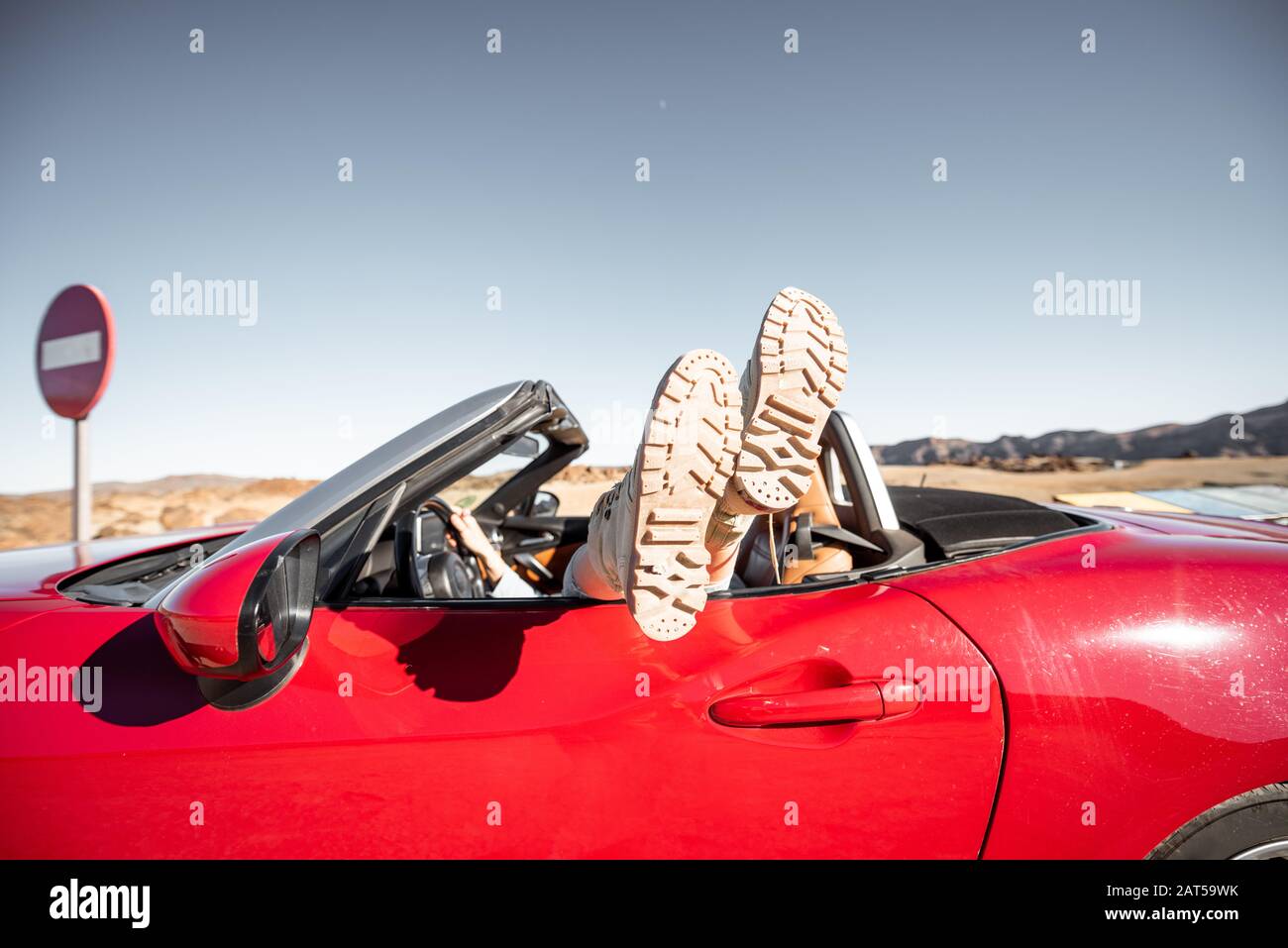 Donna che viaggia su un'auto sportiva convertibile, tirando le gambe fuori  dal finestrino. Vista laterale sulla vettura rossa con scarpe da trekking  Foto stock - Alamy