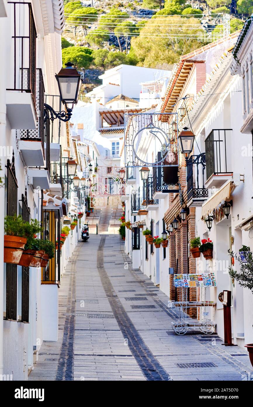 Villaggio collinare di Mijas, strada vuota che conduce in su, case residenziali dipinte di bianco con le piante appese sulle pareti, Málaga, Costa del Sol, Spagna Foto Stock