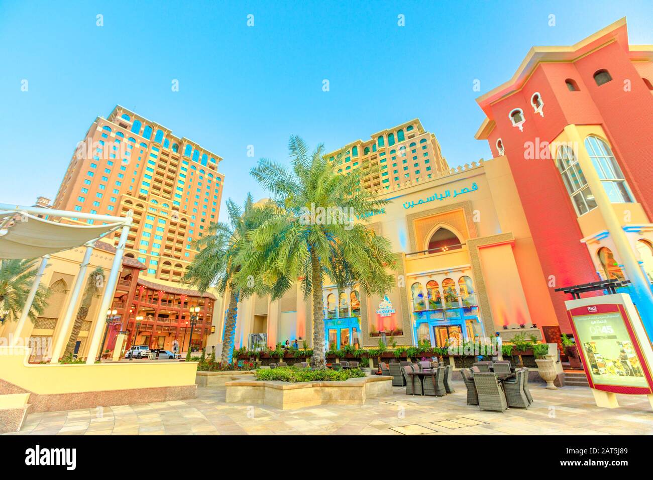 Doha, Qatar - 17 febbraio 2019: Ristoranti e palme lungo il lungomare pedonale del porto in Arabia al Pearl-Qatar, Doha. Golfo Persico in Foto Stock