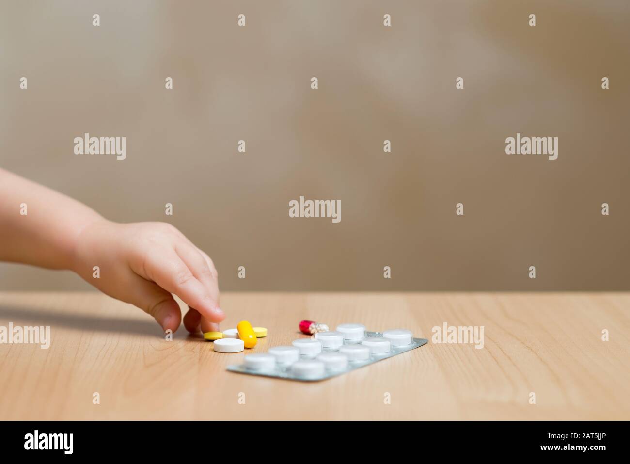 La mano del bambino prende le pillole dal tavolo Foto Stock