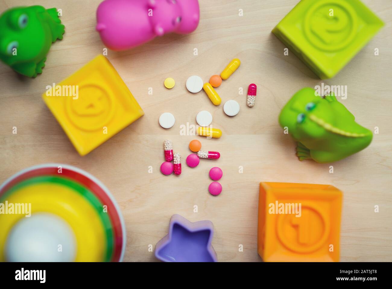 le pillole multicolori si trovano su un tavolo con i giocattoli per bambini mescolati Foto Stock