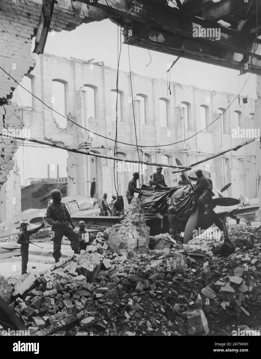 Rimozione di Tarps che copre Cockpit of Fighter Plane, uomini di 4046th QM Truck Co. Ricerca di strumenti e Dashboard Nome Piastre, entrambi leggero souvenir per mailing Home, Oschersleben, Germania, fotografia di Sgt. J. Pazen, U.S. Army Signal Corps, maggio 1945 Foto Stock