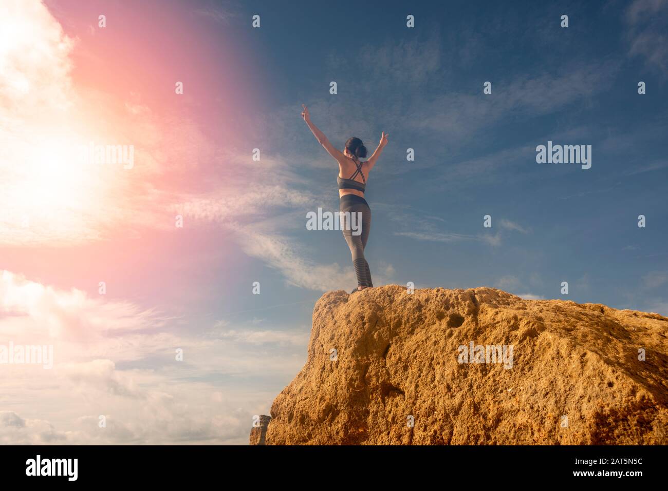 donna con le braccia sollevate contro il cielo, di fronte al sole. Concetto di libertà. Foto Stock
