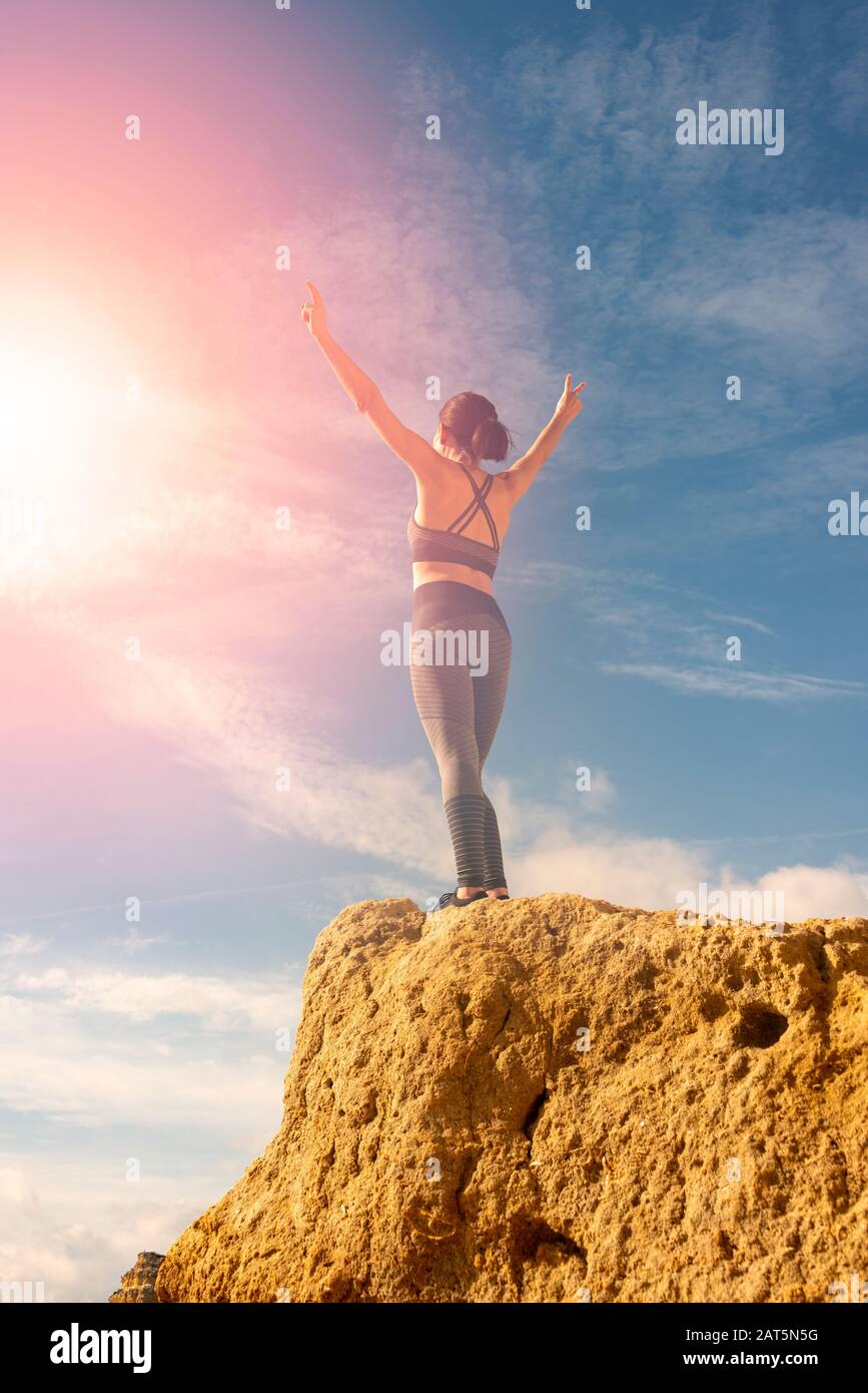 donna con le braccia sollevate contro il cielo, di fronte al sole. Concetto di libertà. Foto Stock