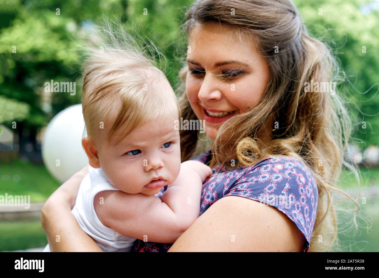 Bella mamma bionda e figlio neonato nelle braccia del parco Foto Stock