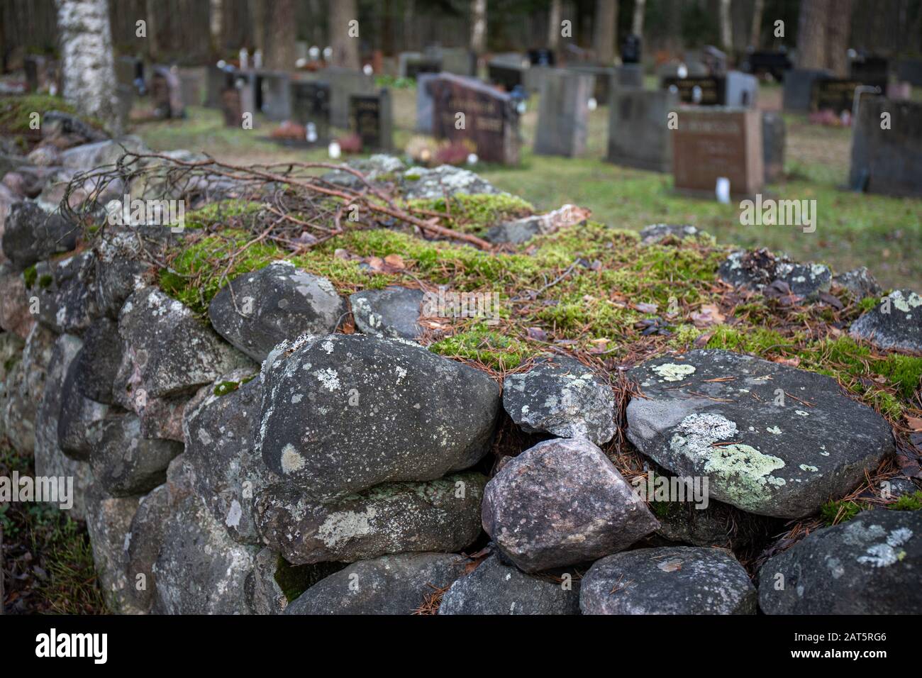 Lapidi dietro muro di pietra cimitero Foto Stock