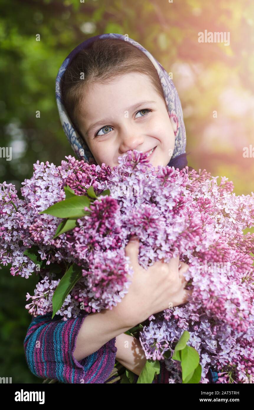 Una bambina con un bouquet di lillà nelle sue mani Foto Stock