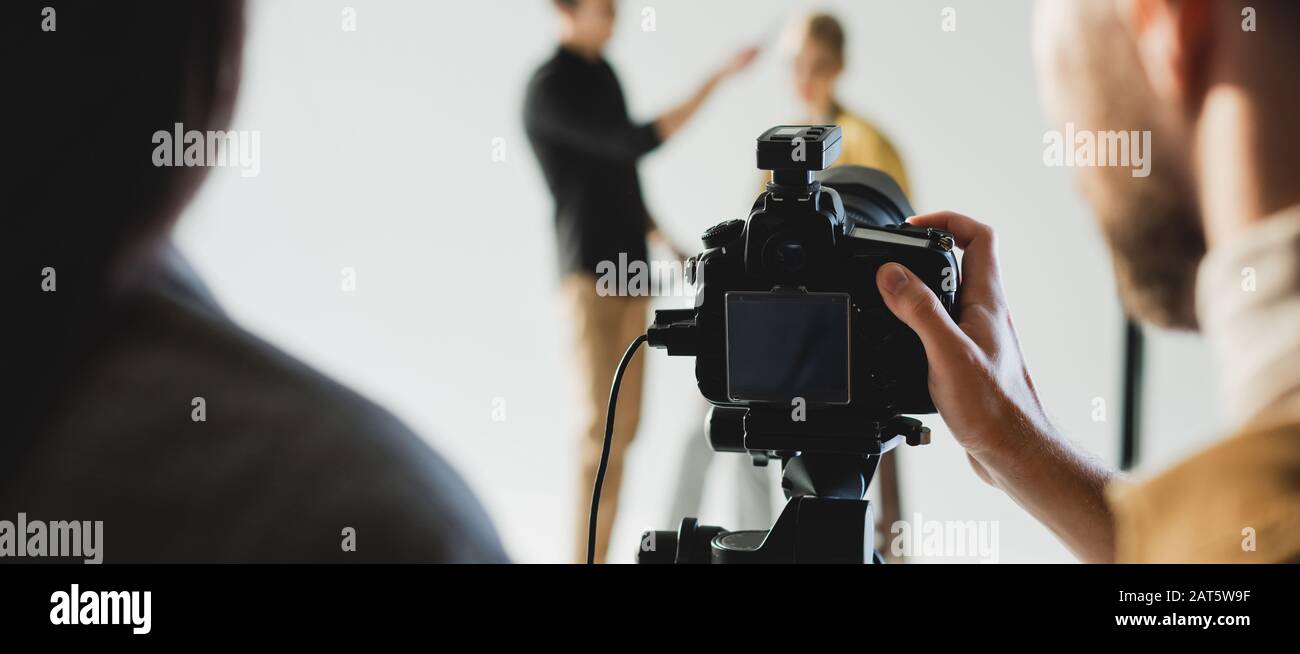 scatto panoramico del produttore e del photographer che scatta la foto del modello e del hairstylist sul backstage Foto Stock