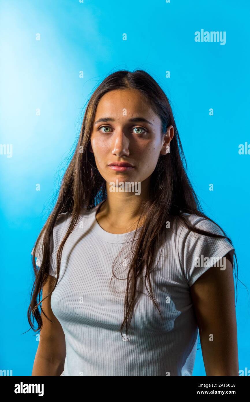 Ritratto di giovane donna medio orientale su sfondo blu studio. Scatto medio. Guardando la fotocamera. Foto Stock